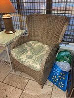 Front view of brown plastic wicker armchair with green paisley cushion