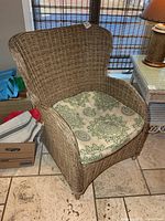 Front angled view of resin wicker armchair with cushion
