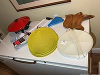 Group view of all items on countertop: electric wok, mesh covers, mandoline, blue pizza container, wooden tray, Tupperware carrier