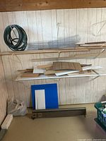 Shelved materials including wire coil, chicken wire roll, assorted boards, table leaf, heater at bottom