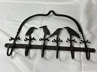 Front view of cast iron rack showing birds, five hooks, arched frame