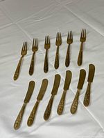 Top view showing six forks and six knives arranged on cloth