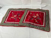 Two red silk embroidered pillow covers side by side