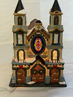 Front view of illuminated porcelain church showing twin steeples and stained glass window
