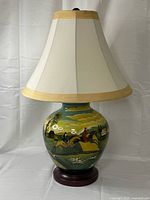 Lamp front view showing ceramic base, painted scene, shade, wooden base