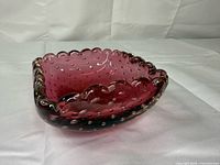 Oblique view showing cranberry body, clear scalloped rim, internal bubbles