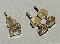 Pair of round stud earrings and single square stud earring with backs