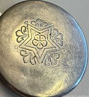 Close-up of engraved lid star-flower motif on one cup