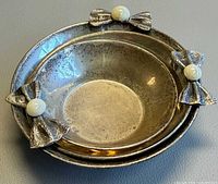Top view of three stacked silver bowls showing bow and pearl decoration