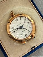 Front view of Birks alarm pocket watch inside box showing dial, crowns and loop