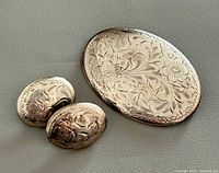 Front view of brooch and earrings showing engraved floral pattern