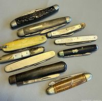Top-down view of all ten folding knives showing variations in handle materials and blade positions