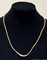 Necklace on black bust showing graduated pearls and overall length