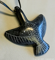 Front view of carved stone bird pendant showing incised details