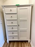 Front view of white armoire showing six drawers and cupboard door