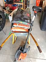 Overall lot showing trimmer, wheelbarrow loaded with mulch bags