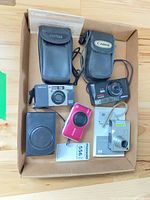 Overview of box containing four cameras, three cases, two manuals