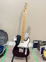 Full view of Fender Telecaster on stand with strap visible