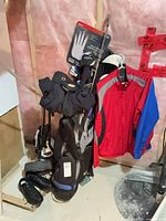 Golf bag on cart with clubs, gloves, jackets, shoes