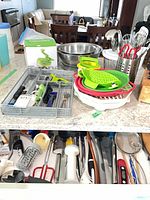 countertop view showing mixing bowls, collapsible strainers, utensil holder, cutlery tray, measuring cup, drawer with utensils