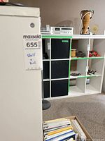 White cube shelf unit with black bins visible