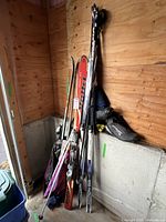 All skis, poles and boots leaning against wall