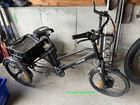 Full view of T-zone black 3-wheel e-bike showing frame, wheels, battery and basket