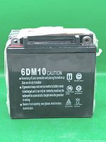 Front view showing 6DM10 model and caution text on black battery