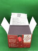Open box showing stack of grey softback sanding sponges and instruction sheet