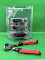 Overview of pliers and blister pack of three folding hex key sets against green background
