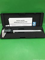 Caliper inside open case with instructions and battery