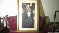 Framed portrait painting placed on red upholstered bench, full view