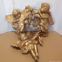 Front view of all three gold-tone cherub ornaments