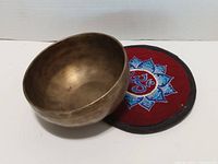 Brass singing bowl resting in red embroidered cushion pad
