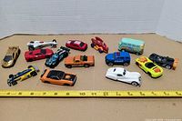 Group shot of fourteen die-cast cars with ruler for size reference