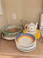 Group of pasta bowls, yellow plates, serving bowl, pie dish, pitcher and teapot