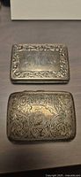 Two sterling silver cigarette cases showing engraved surfaces and patina