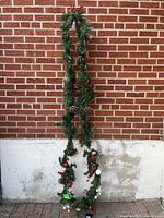Full view of 14 ft green pine garland hanging against brick wall
