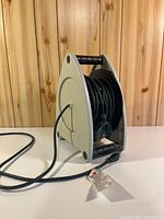 Front view of retractable extension cord on reel showing cord and plug