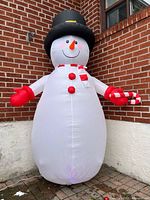 Full view of inflated snowman against brick wall showing overall design and size