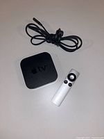 Apple TV unit, remote, power cable displayed on table