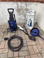 Washer unit with hose, gun, foam bottle, surface cleaner, brush, and box displayed on patio