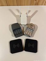 All items grouped: two black wireless pads, white Wi-Fi extender, two battery chargers