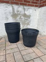 Five black plastic planters stacked and separated