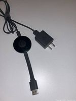 Chromecast with attached HDMI cable and power adapter displayed on surface
