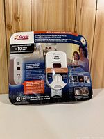 Front of packaged Kidde plug-in carbon monoxide alarm showing device, digital display window, test knob and voice warning label