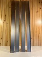 Four grey steel shelves standing upright against wood panel wall