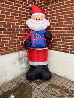 Full view of inflatable Santa standing against brick wall