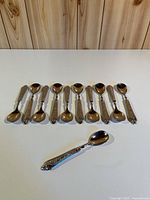 All 11 ornate silver-tone teaspoons displayed