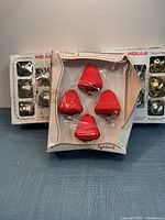 Three vintage ornament boxes: two Holly boxes of silver/gold balls, one Pyramid box of red bells